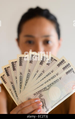 Eine japanische Frau mit 10.000 Yen-Banknoten. Stockfoto