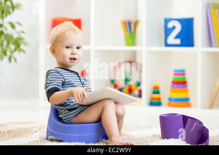 Kleinkind sitzen auf Nachttopf TabletPC spielen Stockfoto