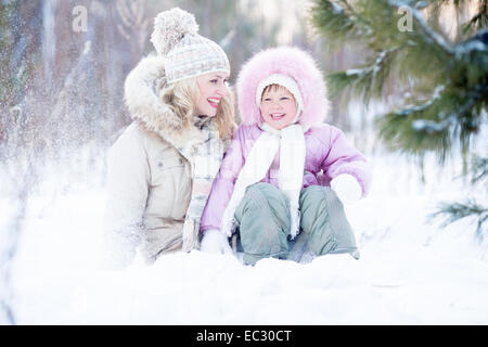 Glückliche Familie sitzen im Schnee im Winter Stockfoto