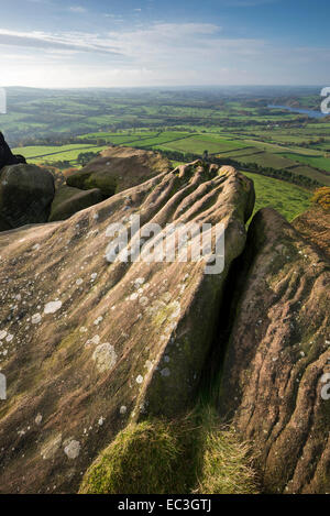 Verwitterte Steinfelsen auf dem Gipfel der Hen Cloud (die Kakerlaken) mit Blick über eine Patchwork-Landschaft darunter. Stockfoto