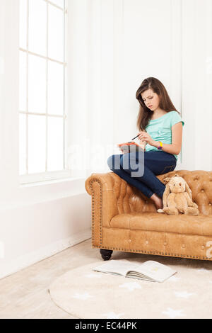 Junges Mädchen mit Tablet auf Couch zu Hause Stockfoto