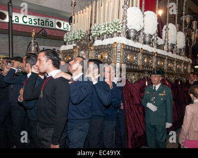 Prozession am Heiligen Abend Dienstag der Osterwoche in Algeciras. Mitglieder der Bruderschaft beim Tragen einer schwere Figur von der Stockfoto