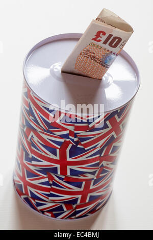 gefaltete £10 Hinweis in Spardose mit Union Jack-Flaggen auf isoliert auf weißem Hintergrund Stockfoto