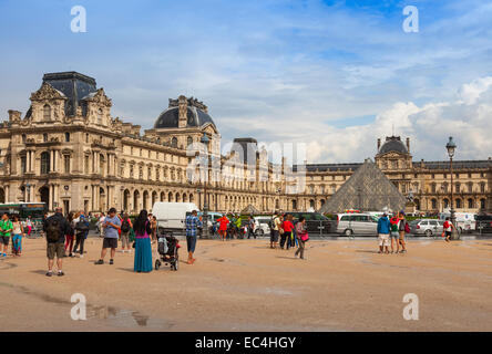 Paris, Frankreich - 7. August 2014: Fassade des Louvre Museums mit Touristen und Autos fahren auf der Straße Stockfoto