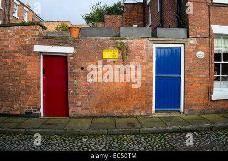 Blaue und rote Holztüren in einer Mauer in Swan Hill, Shrewsbury, Shropshire, England Stockfoto