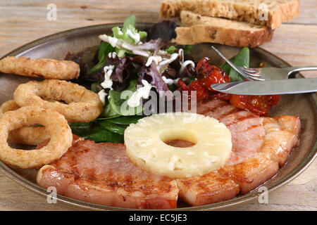 Gegrillter Schinken-Steak mit Zwiebelringen und Ananas Stockfoto