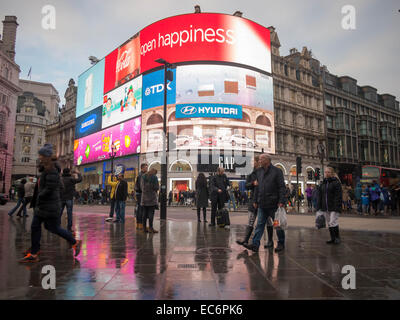 Fußgänger gehen auf eine nasse Fahrbahn am Piccadilly Circus, London, England Stockfoto