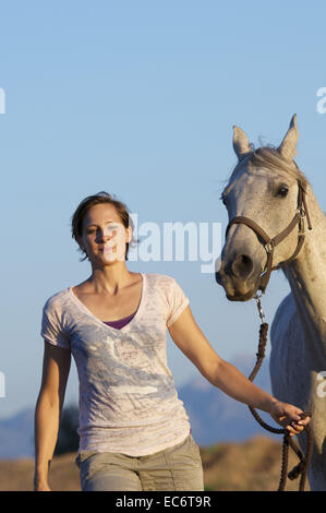 junge Frau, die ein weißes Pferd mit halter Stockfoto