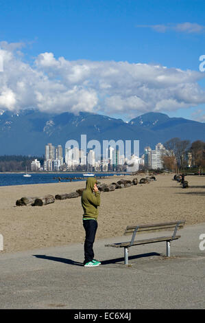 Junge Mann trägt einen Hoodie sprechen auf einem Handy auf Kits Beach, Kitsilano, Vancouver, BC, Kanada Stockfoto