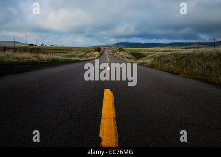 Eine ländliche Landstraße Ranchland mit Gewitterwolken über Kopf auf der Durchreise. Stockfoto