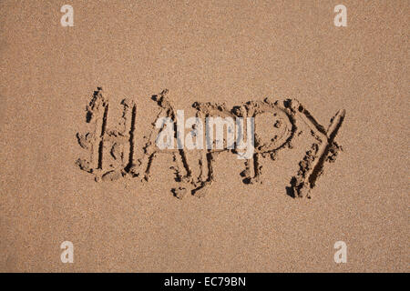 glückliches Wort geschrieben am braunen Sandboden Ebbe Strand Meeresküste in Spanien Europa Stockfoto
