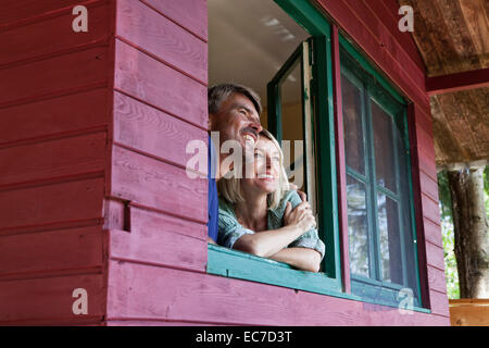 Gerne älteres paar Blick aus Fenster von Summer house Stockfoto