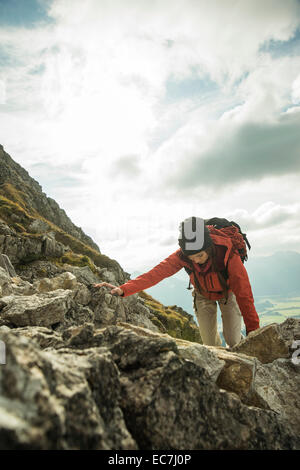 Österreich, Tirol, Tannheimer Tal, junge Frau, die auf Felsen klettern Stockfoto