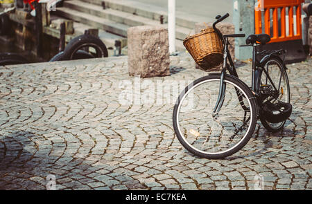 Oldtimer Fahrrad mit Korb auf Bürgersteig geparkt. Fahrrad-Parken In der Großstadt. Getönten Sofortbild Stockfoto