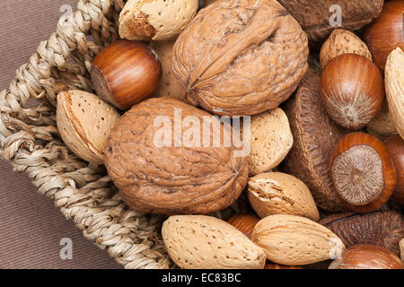 Korb in verschiedenen Arten von Nüssen in Muscheln, Paranüsse, Mandeln, Haselnüsse und Walnüsse zu erreichen. Stockfoto