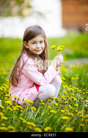 Mädchen sitzen im Blumenfeld Stockfoto