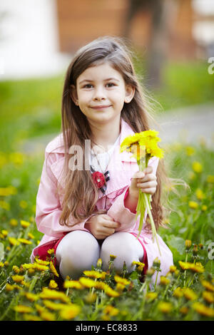 Mädchen sitzen im Blumenfeld Stockfoto