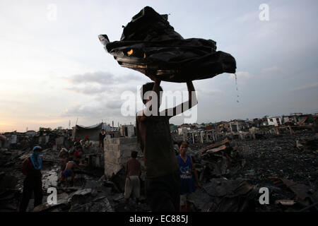 Malabon City, Philippinen. 10. Dezember 2014. Ein Bewohner sammelt wiederverwendbaren Materialien von verbrannten Häuser, nach ein Brand einem Slumviertel in Malabon Stadt, den Philippinen, 10. Dezember 2014 getroffen. Sechs Menschen wurden verletzt in das Feuer, die 200 Häuser und linken 400 Familien obdachlos dem Erdboden gleichgemacht. © Rouelle Umali/Xinhua/Alamy Live-Nachrichten Stockfoto