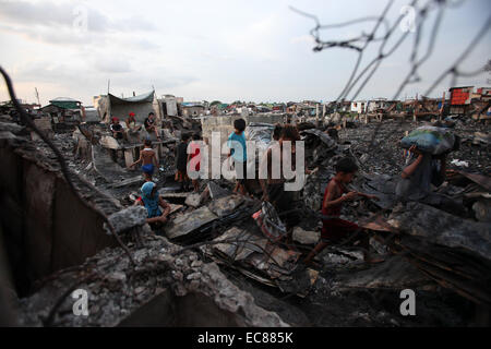 Malabon City, Philippinen. 10. Dezember 2014. Einwohner sammeln wiederverwendbaren Materialien aus verbrannten Häusern, nachdem ein Feuer einem Slumviertel in Malabon Stadt, den Philippinen, 10. Dezember 2014 getroffen. Sechs Menschen wurden verletzt in das Feuer, die 200 Häuser und linken 400 Familien obdachlos dem Erdboden gleichgemacht. © Rouelle Umali/Xinhua/Alamy Live-Nachrichten Stockfoto