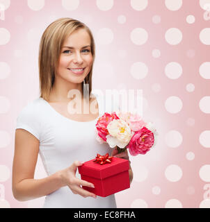 lächelnde junge Frau mit Geschenk-Box und Blumen Stockfoto