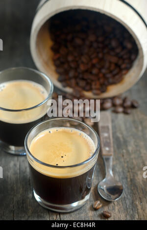 zwei Tassen Kaffee und Kaffeebohnen auf alten hölzernen Hintergrund Stockfoto