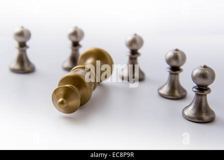 Klassisches Schachspiel - Bauern umkreiste eines gefallenen Königs isoliert Stockfoto