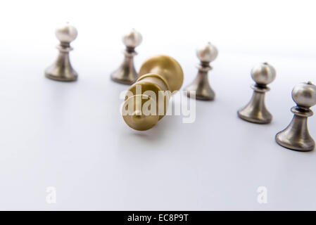 Klassisches Schachspiel - Bauern umkreiste eines gefallenen Königs isoliert Stockfoto