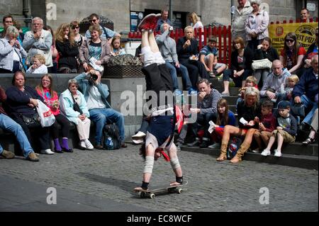 Eine Edinburgh Festival Fringe Darsteller Hand steht auf einem Skateboard, wie eine Menge blickt auf Stockfoto