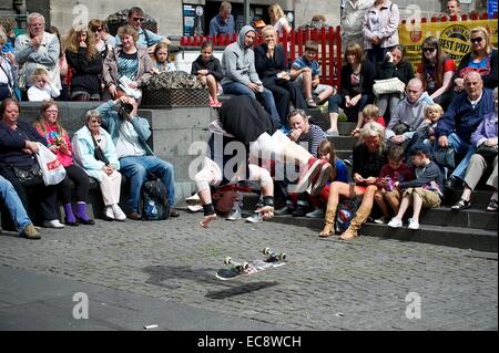 Eine Edinburgh Festival Fringe Darsteller Hand steht auf einem Skateboard, wie eine Menge blickt auf Stockfoto