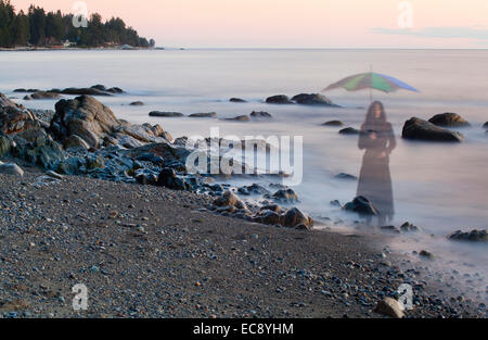 Langzeitbelichtung ein gespenstisches Bild Frau mit Sonnenschirm am Strand in Sechelt, BC, Kanada Stockfoto