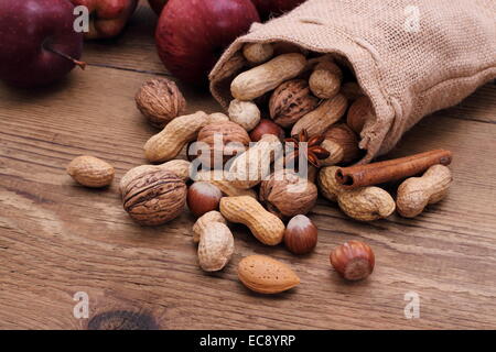 Verschiedenen Nüssen in Jute-Sack-Zimt-sticks, Sternanis und rote Äpfel Stockfoto