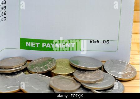 Netto-Zahlung auf eine Gehaltsabrechnung mit Münzen England UK Stockfoto