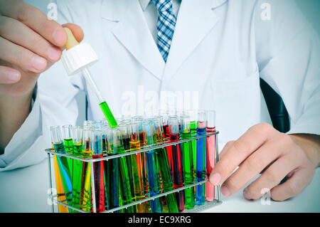 Mann im weißen Kittel mit Reagenzgläsern mit Flüssigkeiten in verschiedenen Farben in einem Labor Stockfoto