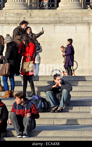 London, England, Vereinigtes Königreich. Menschen auf den Stufen auf dem Trafalgar Square vor der Nationalgalerie Stockfoto