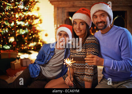 Glückliches Paar in Santa Kappen Toasten mit ihrem Sohn auf Hintergrund Stockfoto