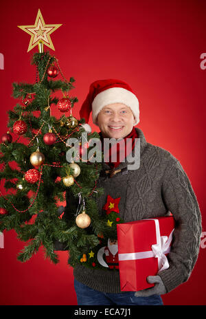 Santa Mann, rote Geschenkbox und Xmas firtree Stockfoto