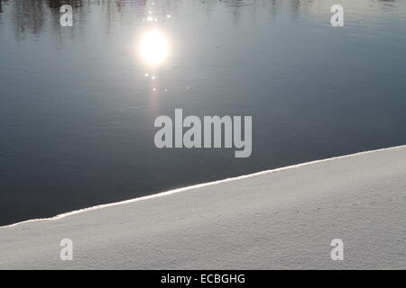 Ufer des Flusses Winter mit Schnee und Splitter Wasser mit helle Reflexion der Sonne in Stockfoto