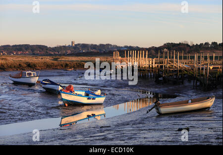 Hölzerne Stege und Boote im Hafen von Morston auf der Küste von North Norfolk mit Dorf Blakeney im Hintergrund. Stockfoto