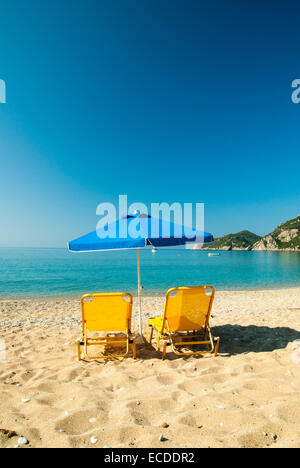 Sonnenliegen und Sonnenschirm (Sonnenschirm) am Strand in Korfu, Griechenland. Stockfoto