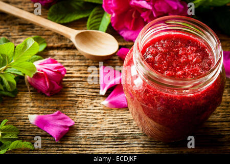 Hausgemachte Marmelade aus Damaskus Blütenblatt stieg auf Holztisch. Fokus auf Glas Stockfoto