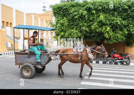 Mann fährt ein Pferd und Wagen durch die gelben Moncada-Kaserne mit Einschusslöchern sichtbar in den Wänden, Santiago De Cuba Stockfoto