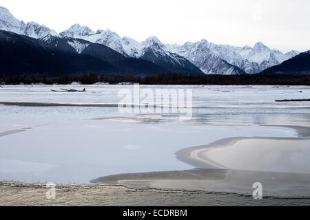 Eis bildet am Chilkat River in der Nähe von Haines Alaska im frühen Winter mit Schnee bedeckten Bergen im Hintergrund in Abend-lig Stockfoto