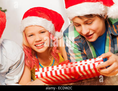 Glückliche Kinder in Santa New Jahr Hüte und mit Geschenk Stockfoto