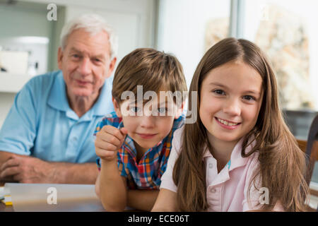 Kinder, die Hausaufgaben mit ihrem Großvater Stockfoto