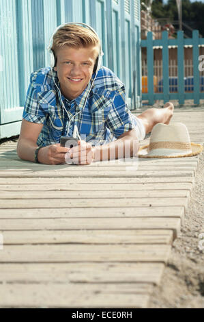 Teenager auf vorne liegen am Strand Musik hören Stockfoto