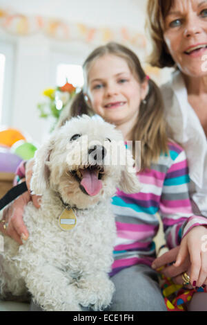 Porträt der Großmutter und Enkel mit Hund im lebenden Raum, lächelnd Stockfoto