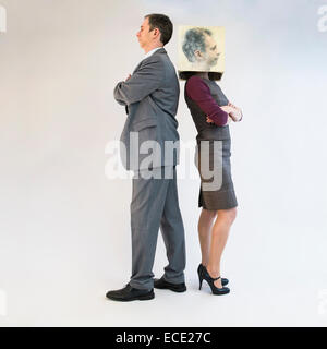 Geschäftsmann steht hinter der Geschäftsfrau mit Maske Stockfoto