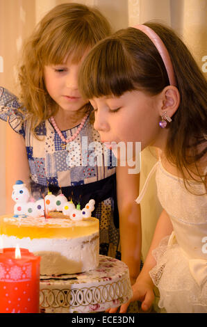 Das Mädchen bläst die Kerzen auf einem Geburtstagskuchen Stockfoto