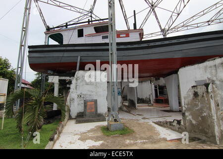 Banda Aceh, Indonesien. 30. November 2014. Ein Fischerboot stützt sich auf die restlichen Wände des Hauses der Familie Misbah in Banda Aceh, Indonesien, 30. November 2014. Das 20-Tonnen-Boot wurde am Pier im Fluss Krueng Aceh, um Kilometer entfernt, andocken, wenn es in das Dach des Hauses während des verheerenden Tsunami 2004 gefegt wurde. Foto: Doreen Fiedler/Dpa/Alamy Live News Stockfoto