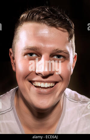 Einem weißen europäischen männlichen Alter 25. Das Bild ist eine Porträtaufnahme Farbe in einem Studio vor einem schwarzen Hintergrund. Stockfoto